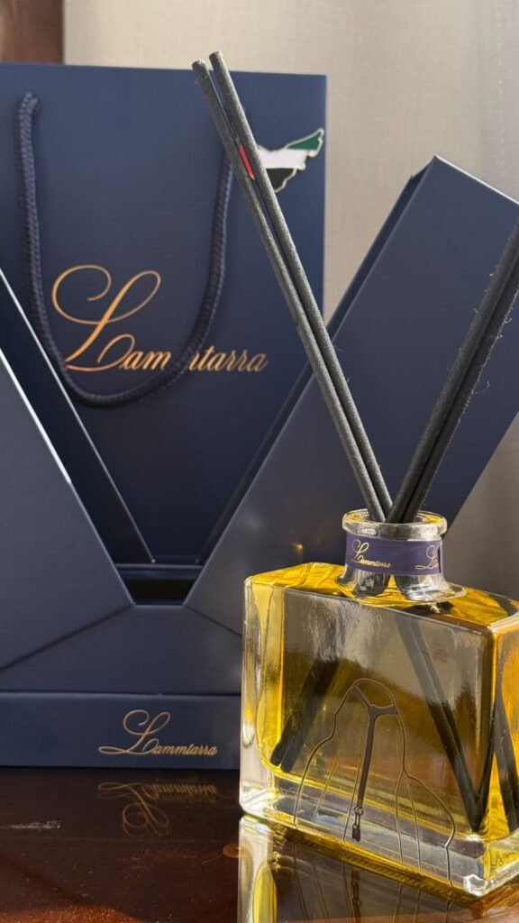 Amber Lammtarra reed diffuser in front of the navy gift box and gift bag
