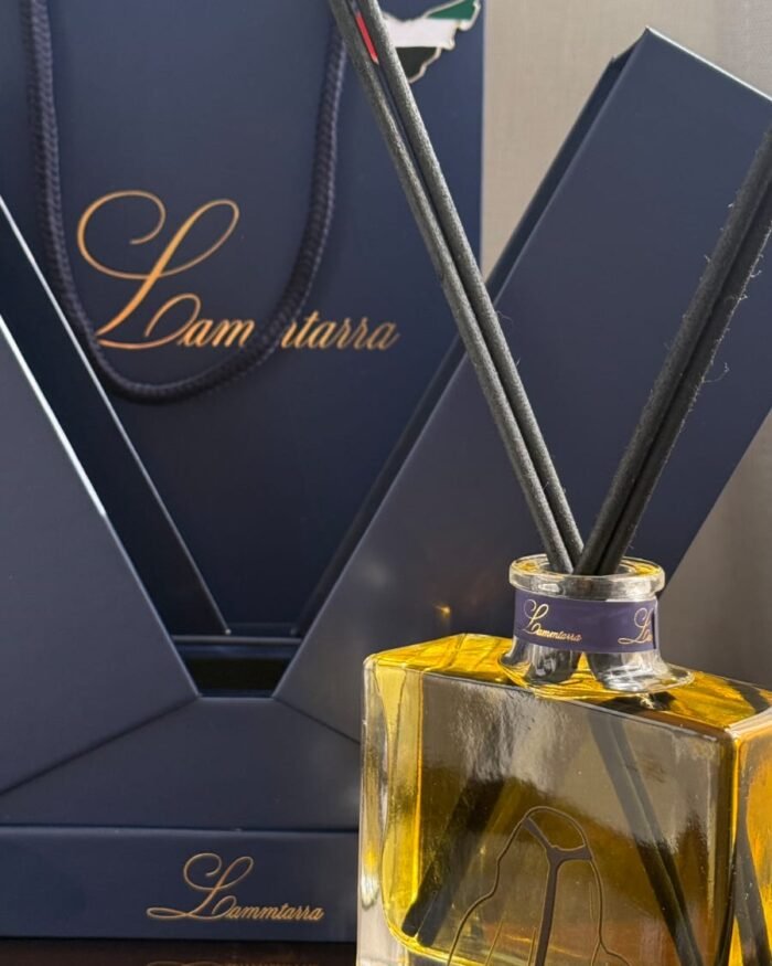 Amber Lammtarra reed diffuser in front of the navy gift box and gift bag