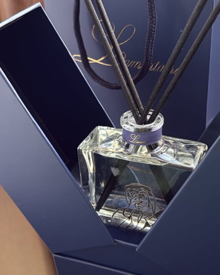 Clear Lammtarra reed diffuser inside its open navy gift box with the gift bag behind